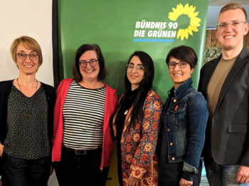 Tanja Josche, Eva Neubert und Henrik Schmidt-Heck mit Saghar Kia und Nina Afschari vor einem Banner von Bündnis 90/Die Grünen. Sie befinden sich in einem Innenraum mit einer gemütlichen Holzvertäfelung nach dem Vortrag.