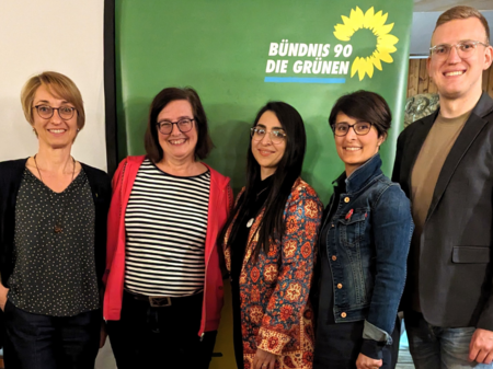 Tanja Josche, Eva Neubert und Henrik Schmidt-Heck mit Saghar Kia und Nina Afschari vor einem Banner von Bündnis 90/Die Grünen. Sie befinden sich in einem Innenraum mit einer gemütlichen Holzvertäfelung nach dem Vortrag.