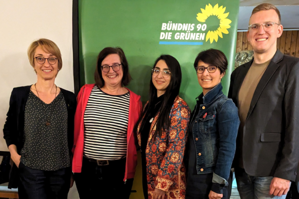 Tanja Josche, Eva Neubert und Henrik Schmidt-Heck mit Saghar Kia und Nina Afschari vor einem Banner von Bündnis 90/Die Grünen. Sie befinden sich in einem Innenraum mit einer gemütlichen Holzvertäfelung nach dem Vortrag.